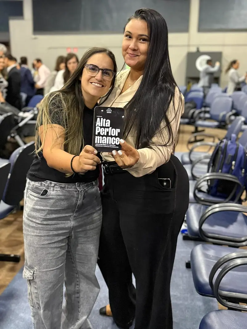 Thayla Varjão com uma colega e o prêmio Alta Performance